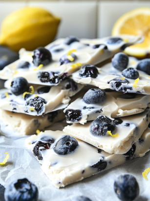 Dairy-free lemon blueberry frozen yogurt bark with blueberries and lemon zest on parchment paper.